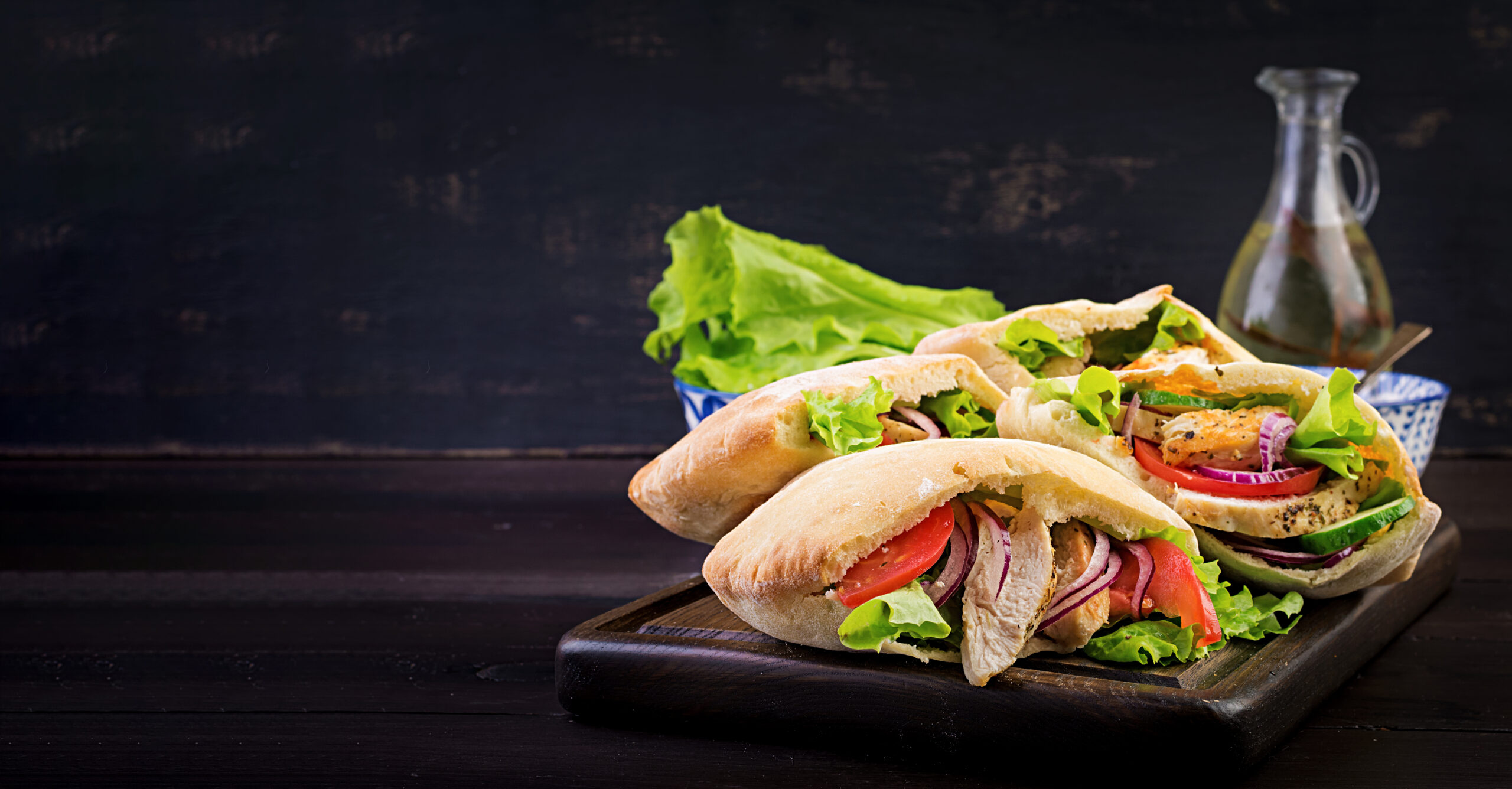 Pita stuffed with chicken, tomato and lettuce on wooden backgrou